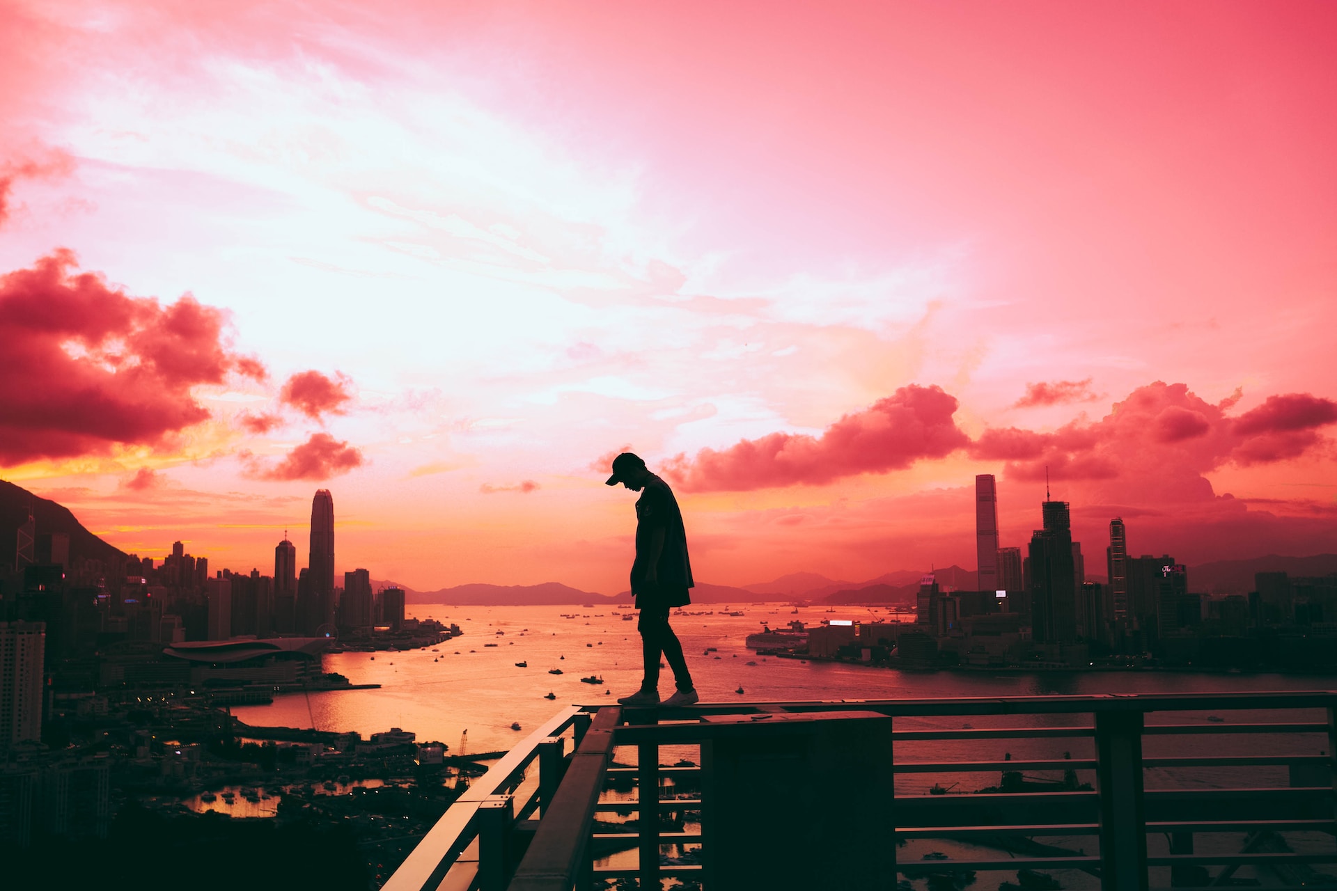 lonely man walking along guardrail over city skyline